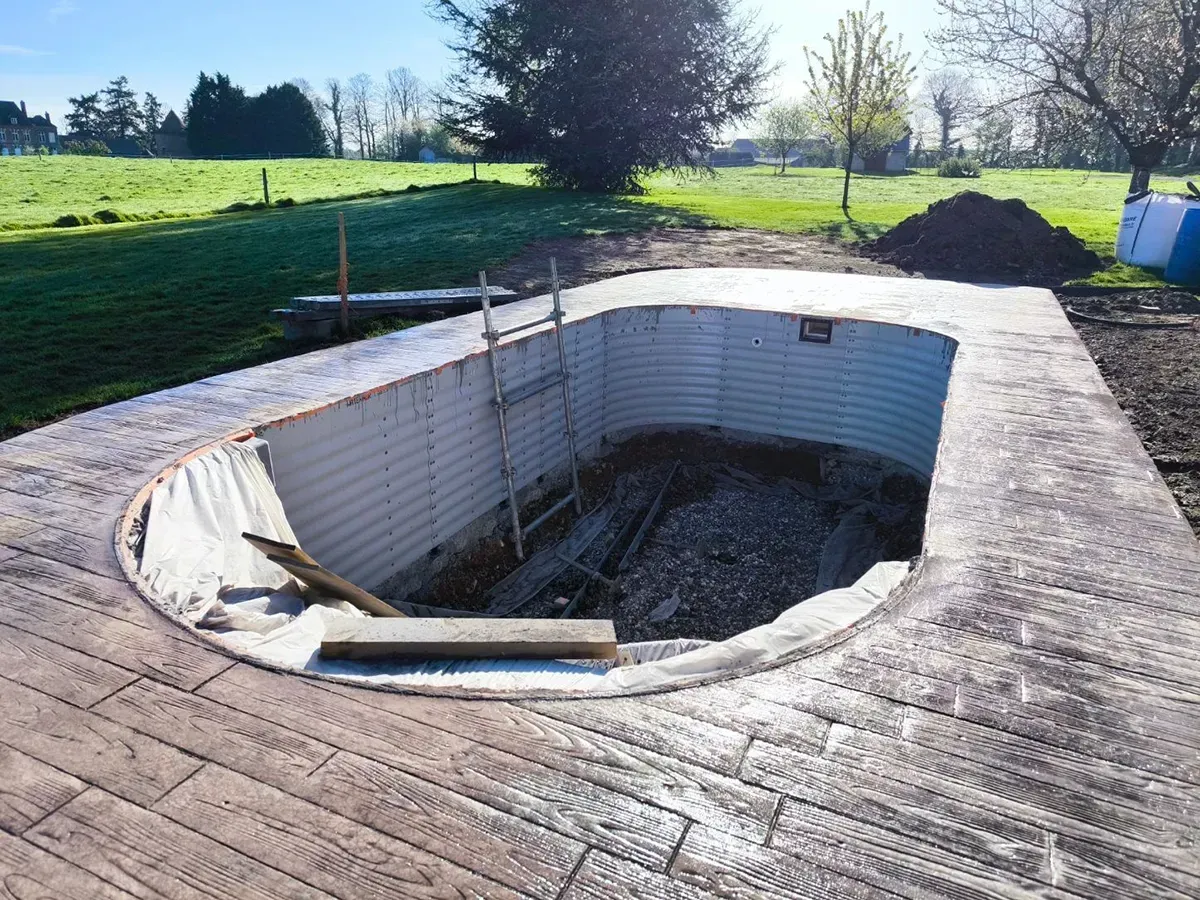 Plage de piscine en béton imprimé effet bois autour d'un bassin en Normandie