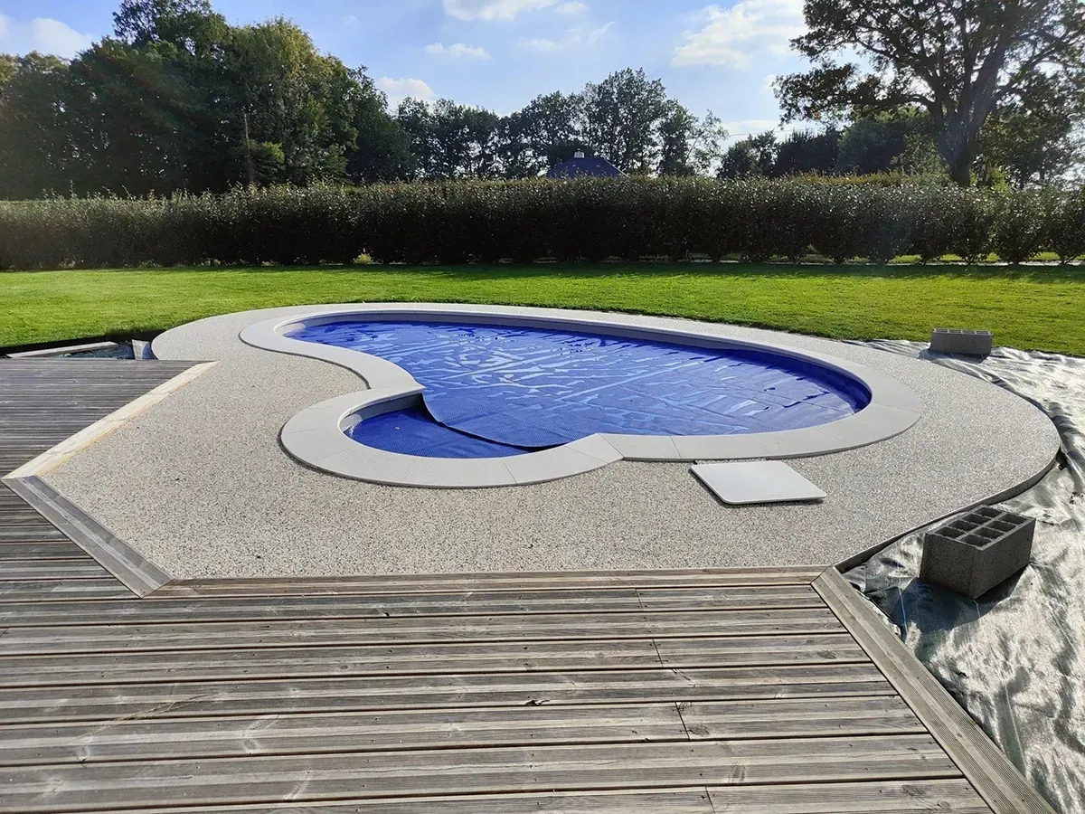 Plage de piscine en moquette de pierre grise drainante réalisée en Normandie