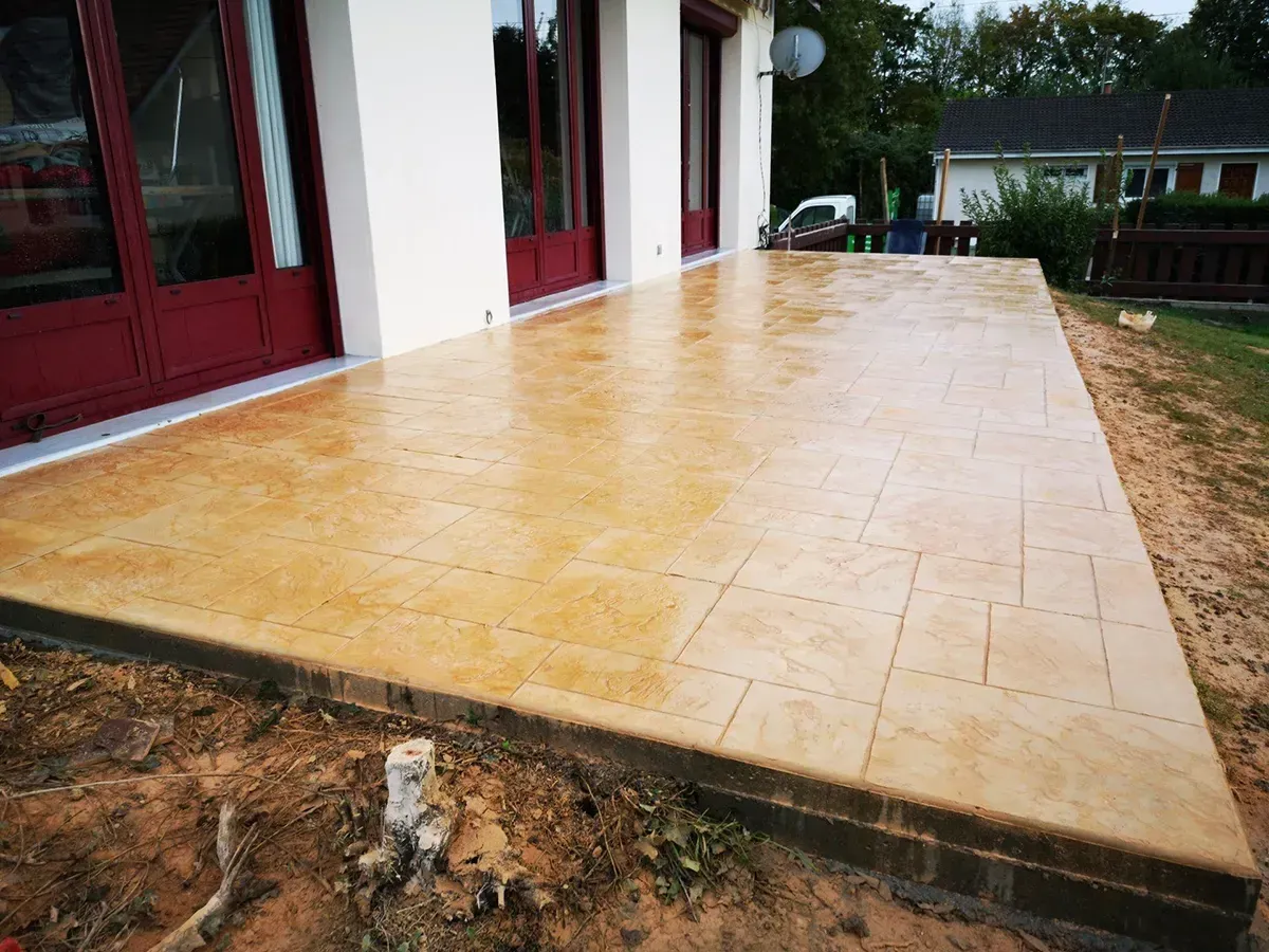 Terrasse en béton imprimé effet pierre de taille ton sable devant une maison